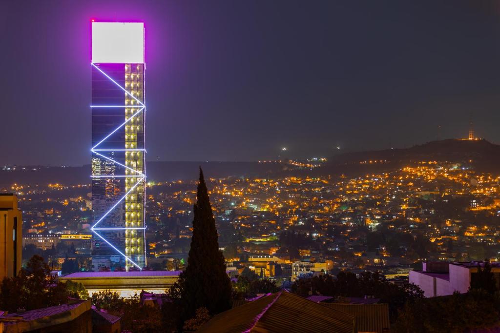 einen beleuchteten Turm mit einer Stadt in der Nacht in der Unterkunft Apartments with wine cellar in Old Tbilisi in Tbilisi City