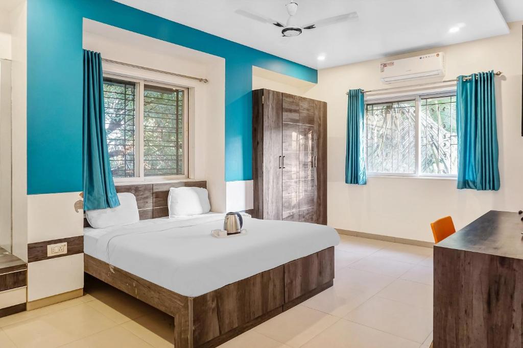 a bedroom with a large bed with blue walls at Super Townhouse 749 The Upper Room Near Pune Airport in Lohogaon