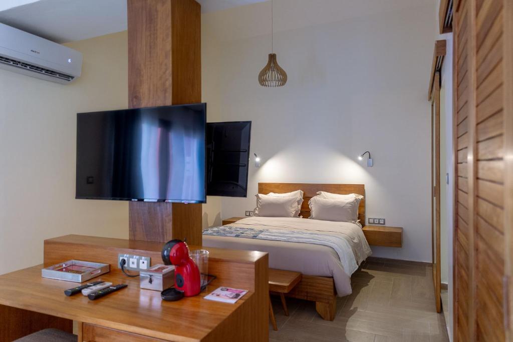 a bedroom with a bed and a desk and a tv at La Madrague-Surf Beach Sea in Dakar