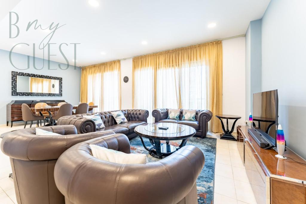 a living room with leather couches and a tv at Spacious Modern 1BR in Business Bay in Dubai