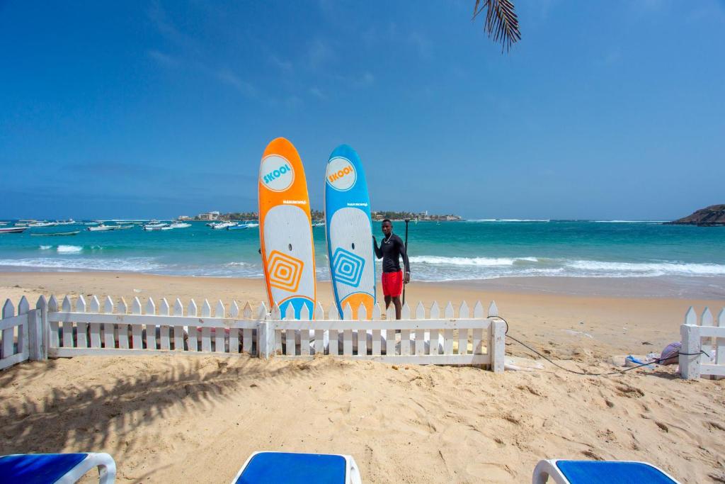 a man standing in front of surfboards on the beach at La Madrague-Surf Beach Sea in Dakar