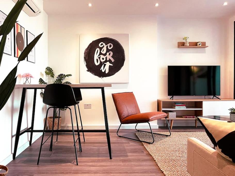 een woonkamer met een tafel en stoelen en een televisie bij Luxe London Pad with Free Parking in Brentford