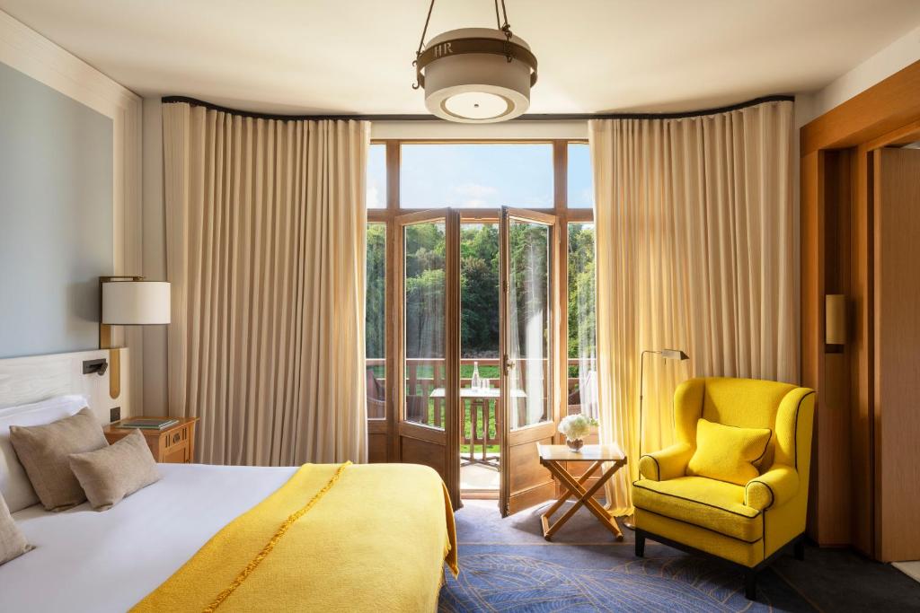 a bedroom with a bed and a yellow chair and a window at Hôtel Royal in Évian-les-Bains