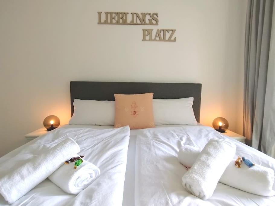 Una cama con sábanas blancas y almohadas. en Cozy home - Willkommen in Aachen - Boxspringbett - Balkon 