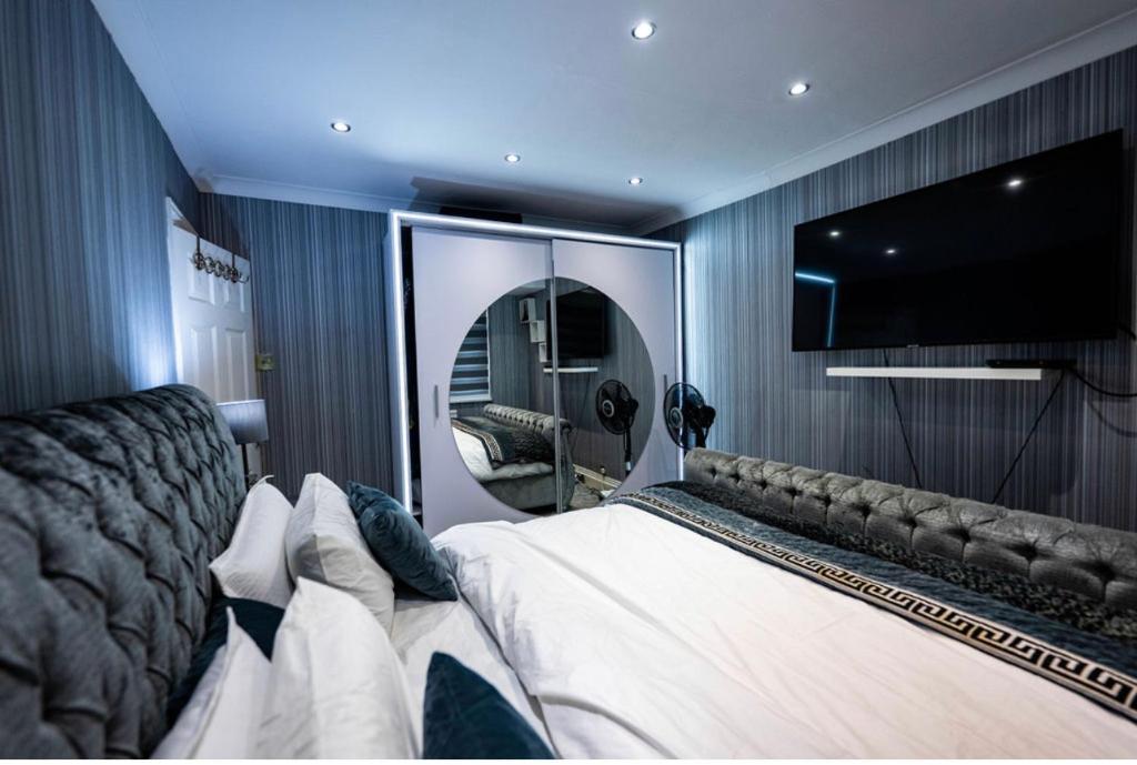 a bedroom with a large bed and a large mirror at UPPAMOST LUXURY HOME LONDOn in Dagenham