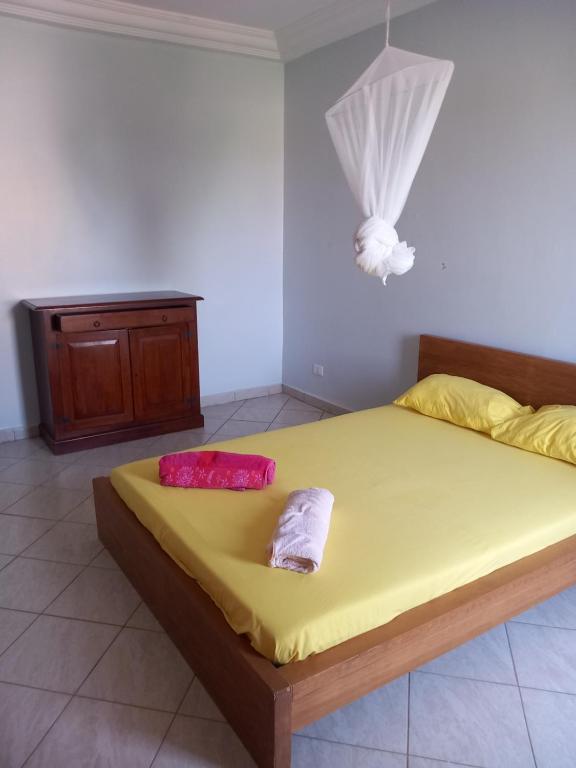 sypialnia z łóżkiem z żółtą pościelą i czerwonymi poduszkami w obiekcie Casa Kassi w mieście Ndéyane