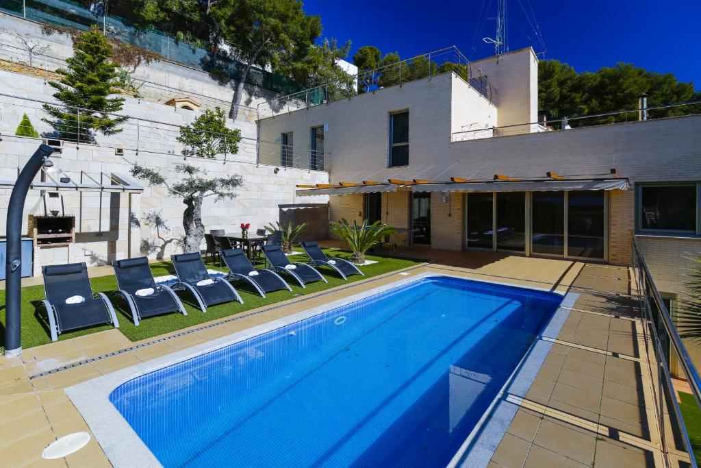 a swimming pool with chairs and a house at Nina Villa Planetcostadorada in Tarragona