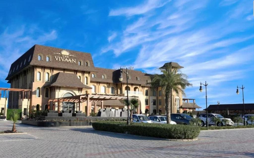 a large building with a palm tree in front of it at The Vivaan Hotel & Resorts Karnal in Karnāl