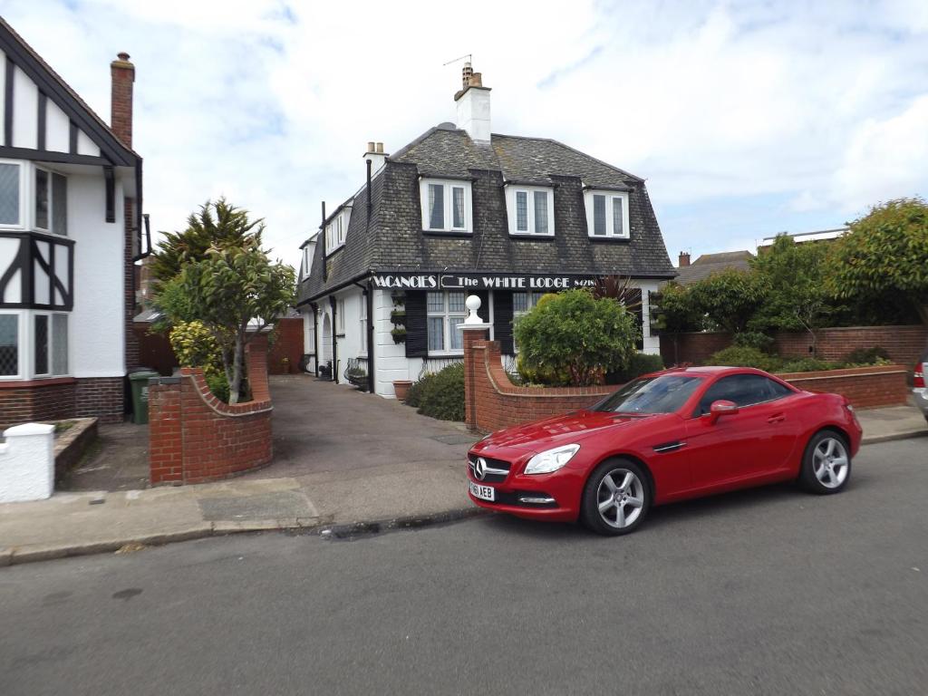 un coche rojo estacionado frente a una casa en The White Lodge en Great Yarmouth