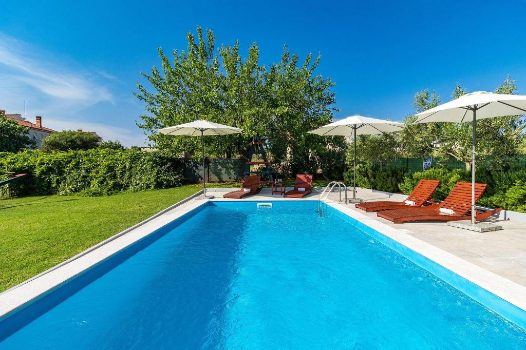 einen Pool mit Stühlen und Sonnenschirmen im Hof in der Unterkunft Casa Luigia in Pula