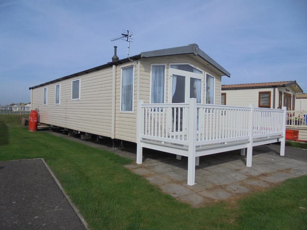 a small house with a porch and a white deck at Kingfisher Bordeaux 8 Berth Central Heated FREE WIFI in Ingoldmells