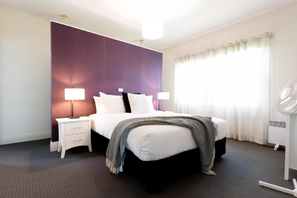 a bedroom with a large bed with a purple wall at Homely Cottage: Near the City Wifi & Parking in Newstead