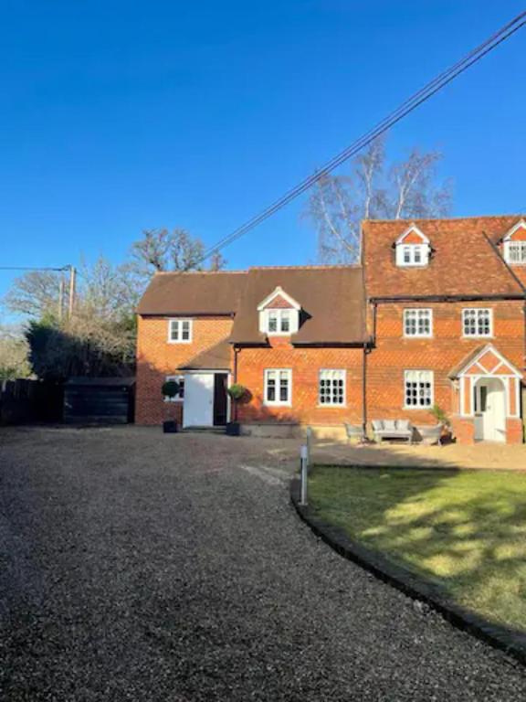 a large orange brick house with a driveway at Mimosa Cottage in Farnham