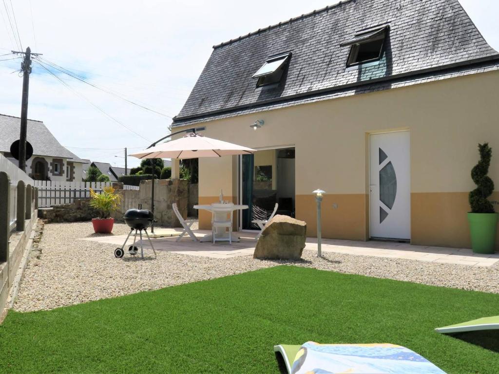 une cour avec une table, un parasol et de l'herbe dans l'établissement Maison Perros-Guirec, 3 pièces, 4 personnes - FR-1-368-301, à Perros-Guirec