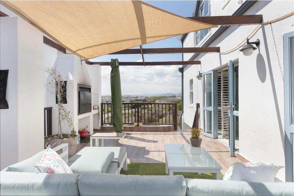 een patio met een bank en een grote parasol bij Big Bay Hilltop Villa in Kaapstad