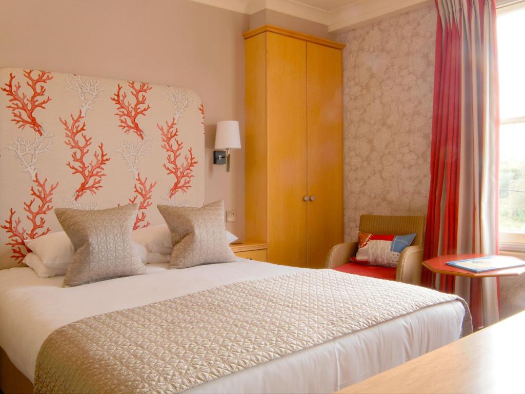 a bedroom with a bed and a chair and a window at Wentworth Hotel in Aldeburgh