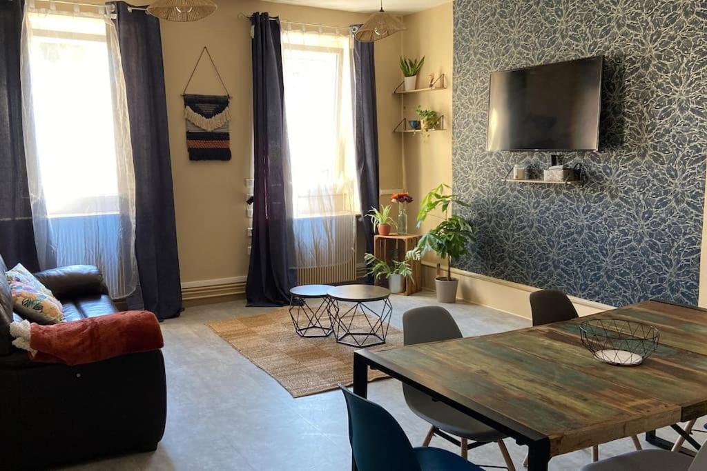 un salon avec une table et une télévision dans l'établissement La maison bleue, à Montcenis