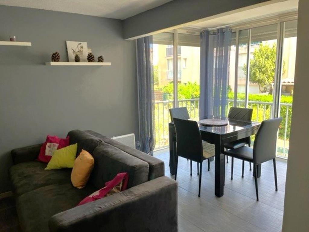 un salon avec un canapé et une table avec des chaises dans l'établissement Charmant T3 au Cap d'Agde avec parking, à 10 min du port et 15 min de la plage - FR-1-749-9, au Cap d'Agde