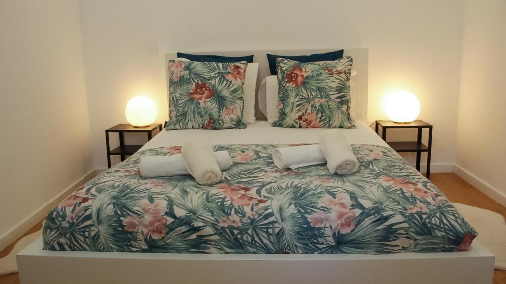 a bedroom with a large bed with a floral bedspread at A m a r - 450m from the beach in São Roque