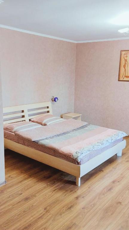een groot bed in een kamer met een houten vloer bij Будинок з Терасою Біля Фонтанів in Oeman