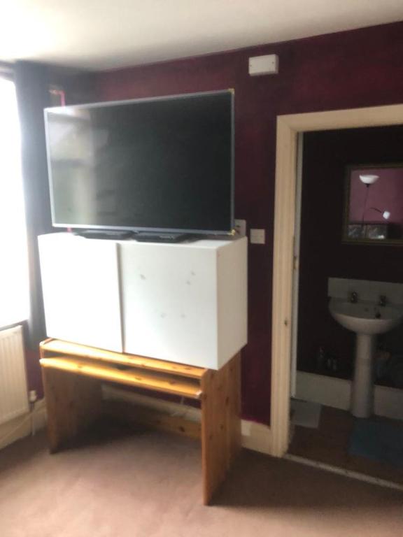 a flat screen tv on a stand in a living room at Room in town centre in Saint Helens
