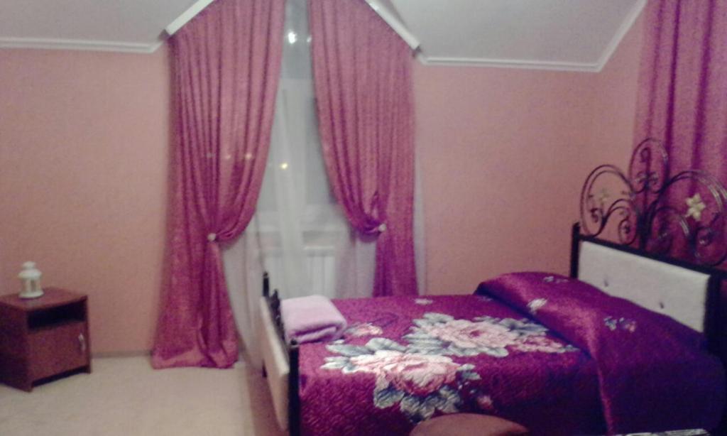バタイスクにあるGuesthouse Agatのピンクのカーテンと花が飾られたベッドが備わるベッドルーム1室が備わります。