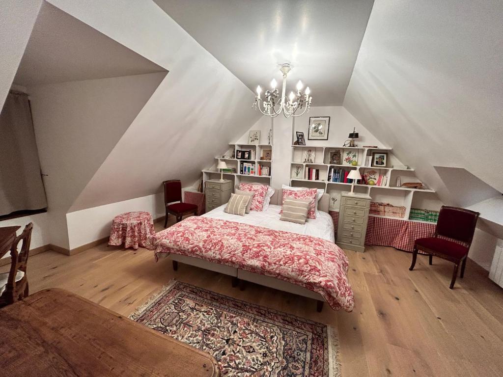 een slaapkamer op zolder met een bed en een kroonluchter bij Une chambre au Pré des fées in Salbris