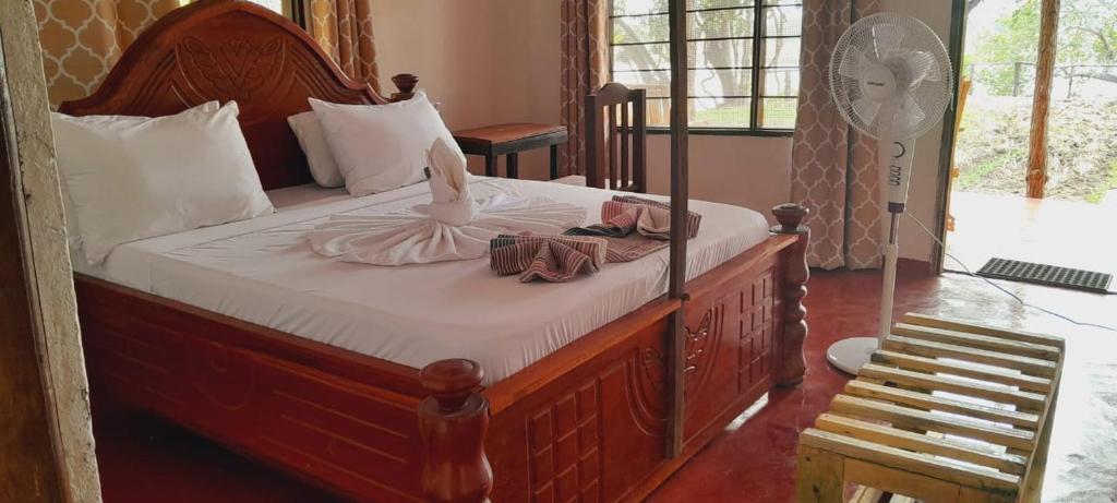 um quarto com uma cama grande e uma estrutura em madeira em SELOUS RIVER VIEW LODGE em Kwangwazi