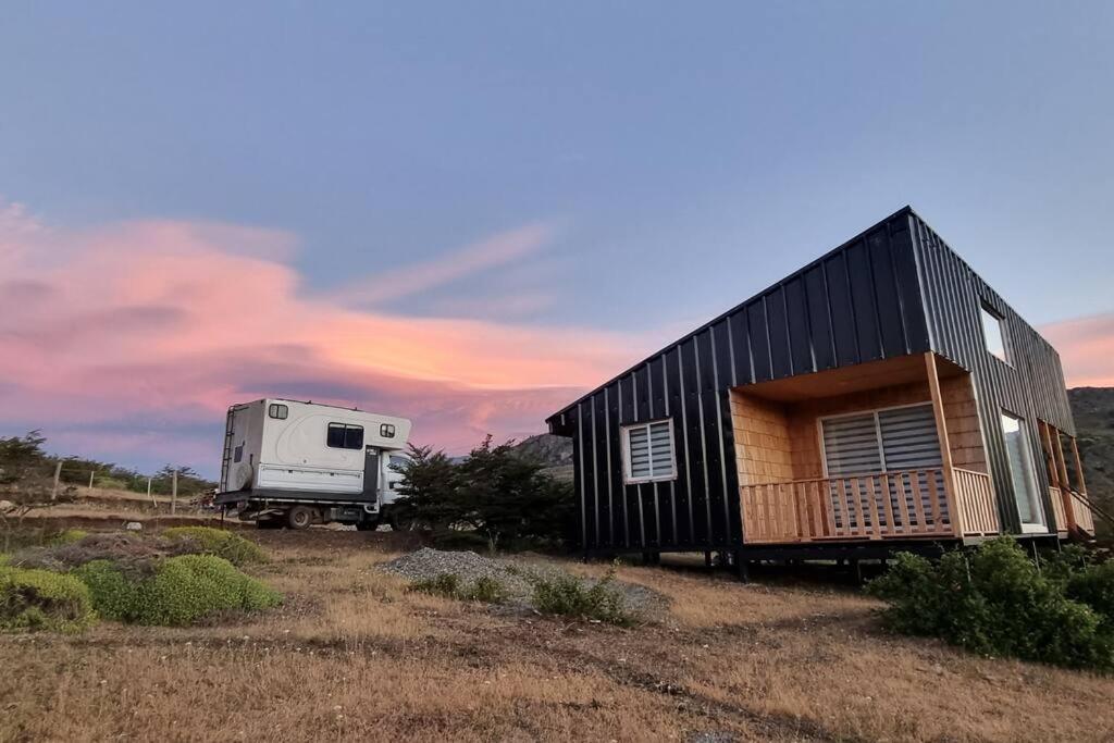 een vrachtwagen geparkeerd naast een klein huis met een trailer bij Descanso garantizado Cochrane in Cochrane