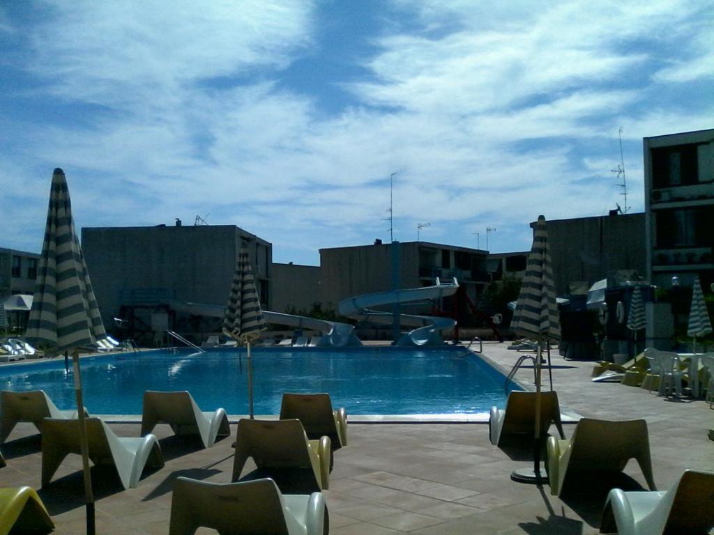 a large swimming pool with chairs and a building at Apparamento Raysol in Agnone Bagni