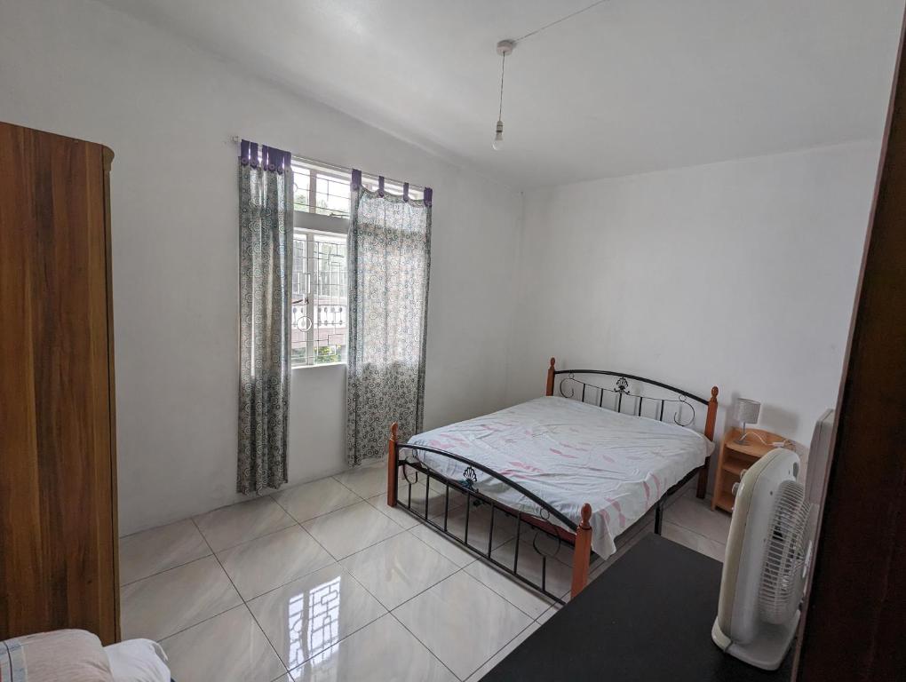 um quarto com uma cama e uma janela em Appartment in residential area em Quatre Bornes