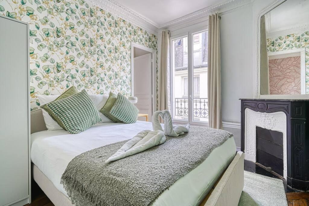 - une chambre avec un grand lit et une cheminée dans l'établissement Green apartment Paris city center, à Paris