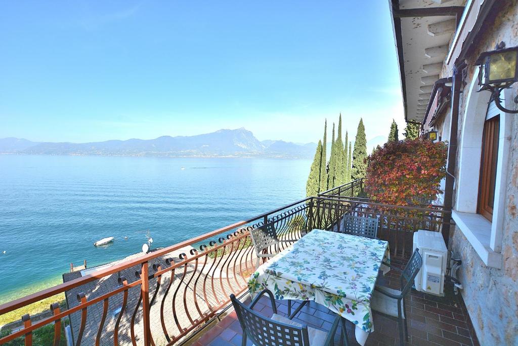 a table and chairs on a balcony overlooking the water at Leonardo Walsh Apartment With Lake View in Albisano