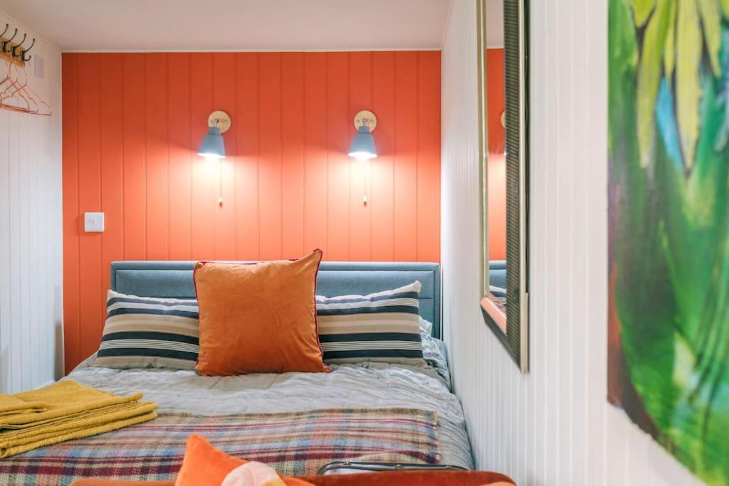 łóżko w pokoju z pomarańczową ścianą w obiekcie The Garden Room w mieście Knighton