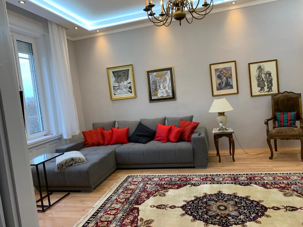 sala de estar con sofá gris y almohadas rojas en Budapest, Graf Teleki Laszlo Appartement en Budapest