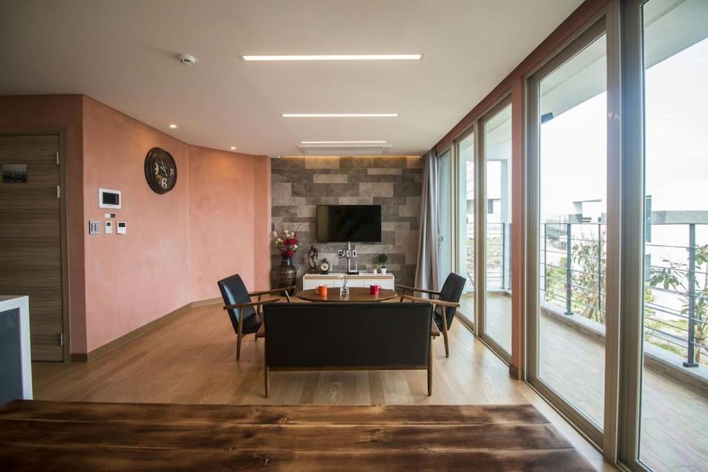 a dining room with a table and chairs and windows at Aewol Penthouse C5 in Jeju