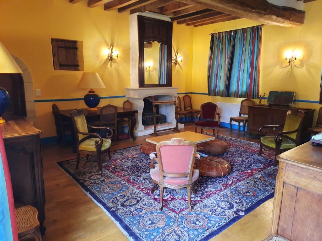 een woonkamer met een open haard en een tafel en stoelen bij Maison de campagne in Ambleny