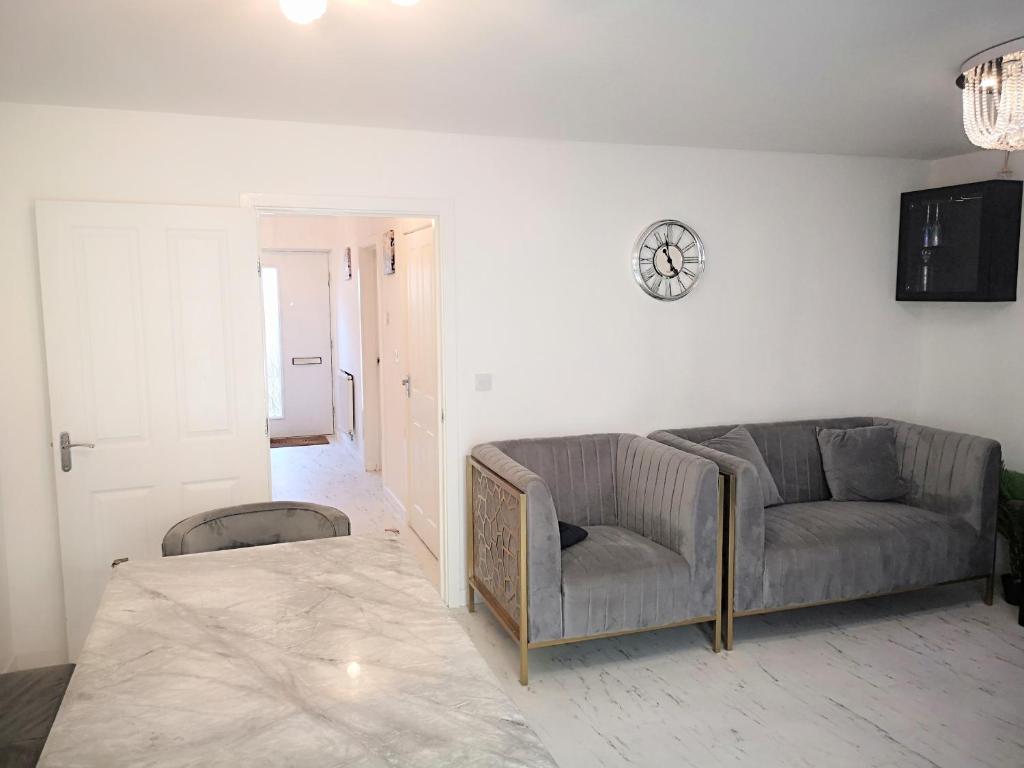 a living room with a couch and a clock on the wall at Harrow Home in Harrow