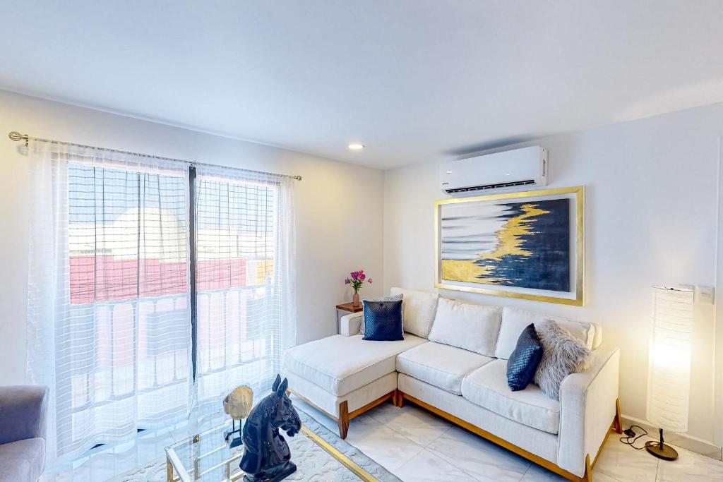 uma sala de estar com um sofá branco e uma grande janela em Alina 203a @ Morgan Residences em Cabo San Lucas