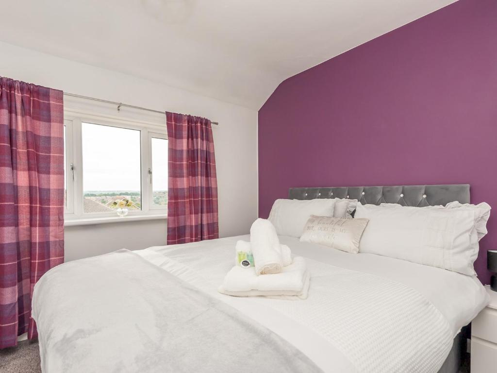 Un dormitorio con una cama blanca con paredes moradas y una ventana en Pass the Keys Large Family Getaway en Leeds