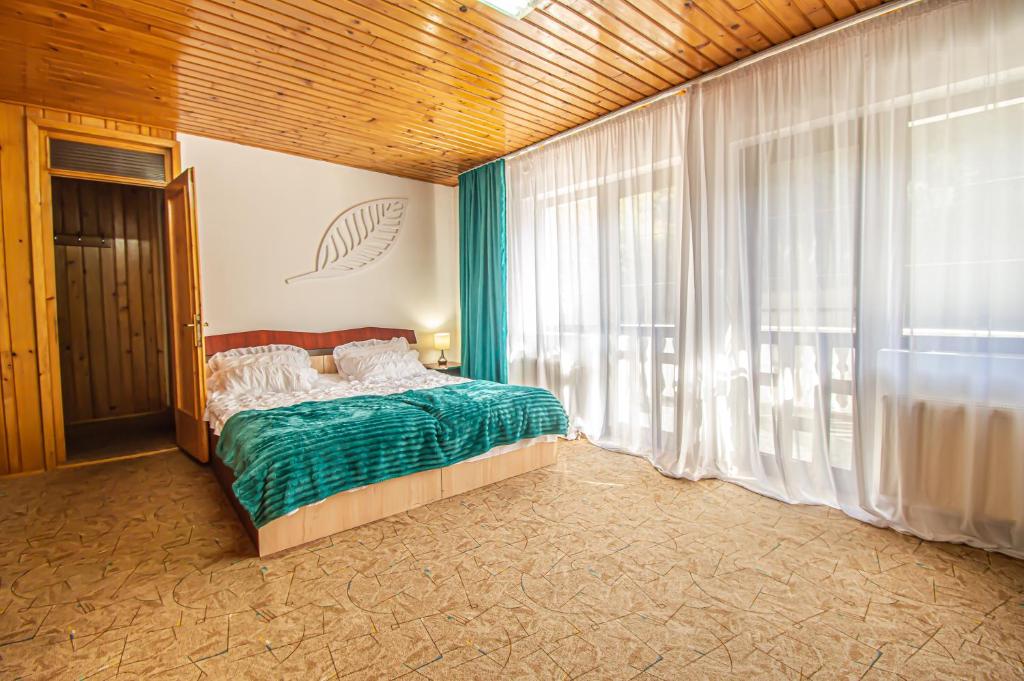 a bedroom with a bed and a large window at Pensiune Forest Park in Baia Mare