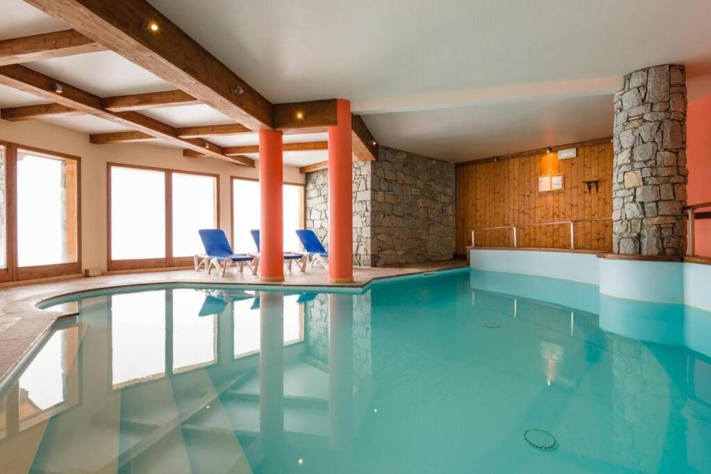 a swimming pool with blue chairs in a building at Vanoise Express Property (Paradiski) in Peisey-Nancroix