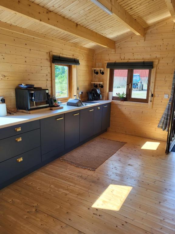 a kitchen in a log cabin with wooden floors at Hot Tub Unique Farm Stay in Pallis Bridge