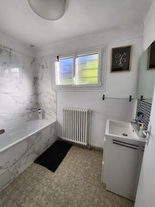 a white bathroom with a tub and a sink at Maison proche Paris JO 2024 in Franconville