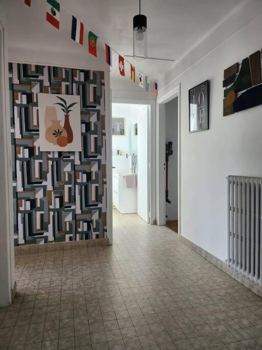 a hallway with a tile floor and a wall with art at Maison proche Paris JO 2024 in Franconville