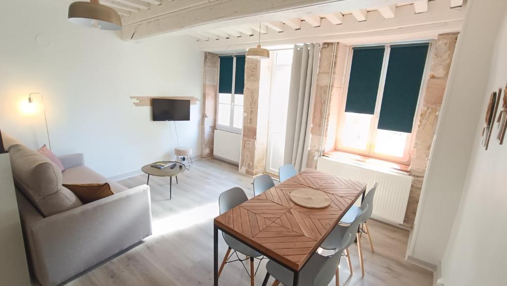ein Wohnzimmer mit einem Tisch und einem Sofa in der Unterkunft Le gîte de Varanges maison de ville au coeur de Givry classée 3 étoiles in Givry