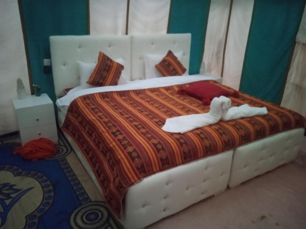 a bedroom with a bed with two white towels on it at Merzouga Chebbi camp in Adrouine