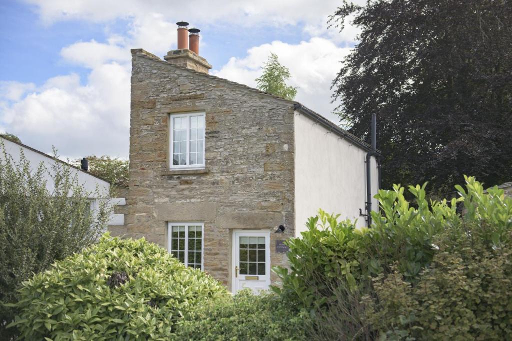 an old stone house with a chimney on top of it at Pond Cottage in West Witton