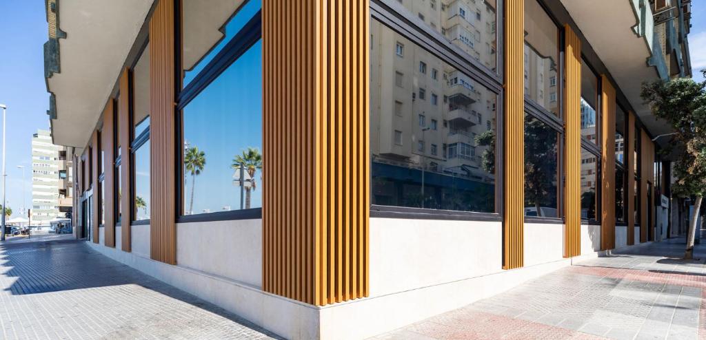 a building with yellow columns on a street at Apartamentos Playa Victoria in Cádiz