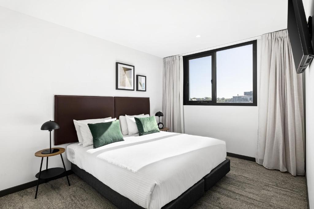 um quarto com uma cama grande e uma janela grande em Quest Geelong Central em Geelong